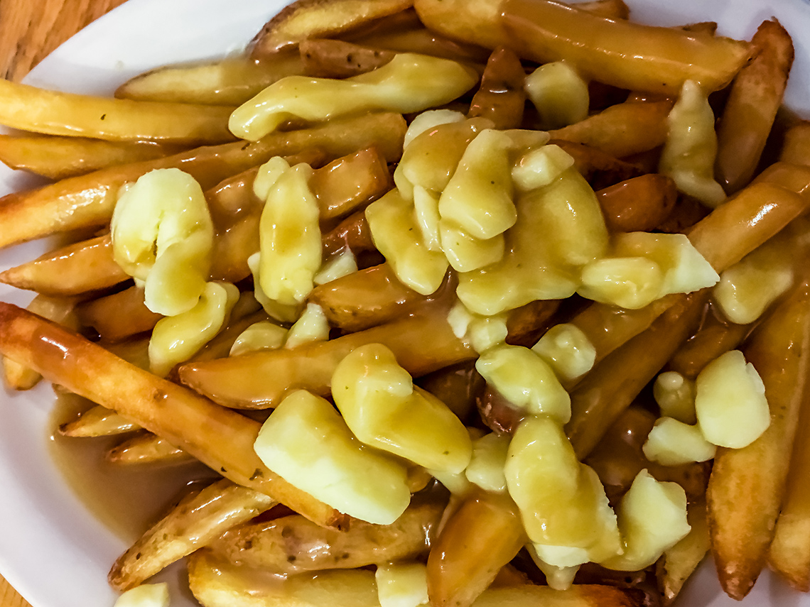 A plate of french fries with gravy and cheese curds.