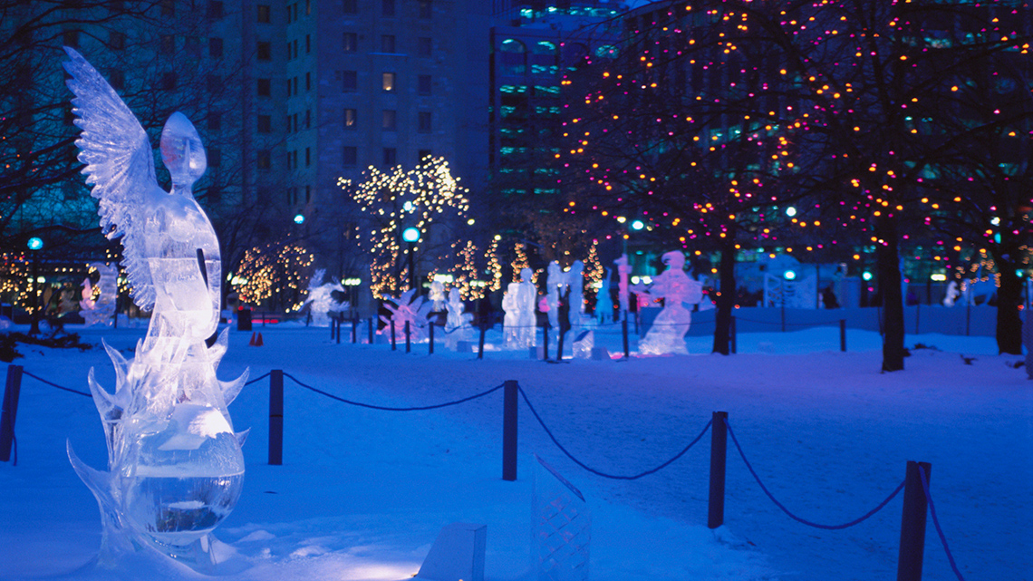 A park at night with illuminated ice sculptures.