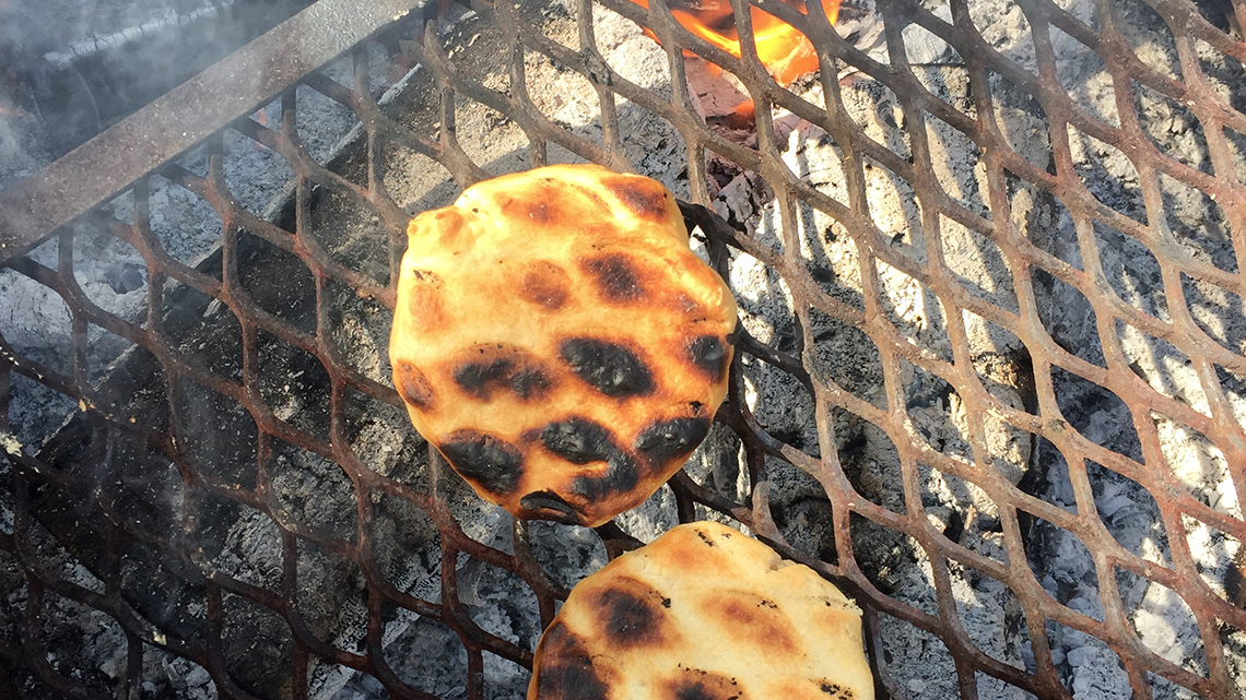 Bannock, a type of bread, cooking over an open flame.