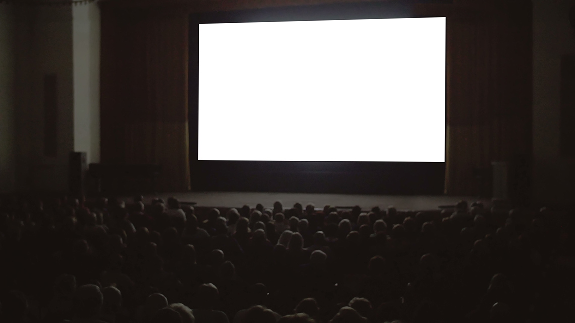 A blank screen at a movie theatre with a full audience.