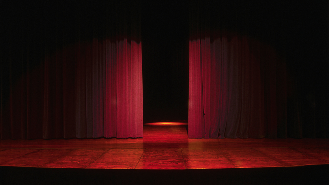 An empty theatre stage with the curtains partly open.