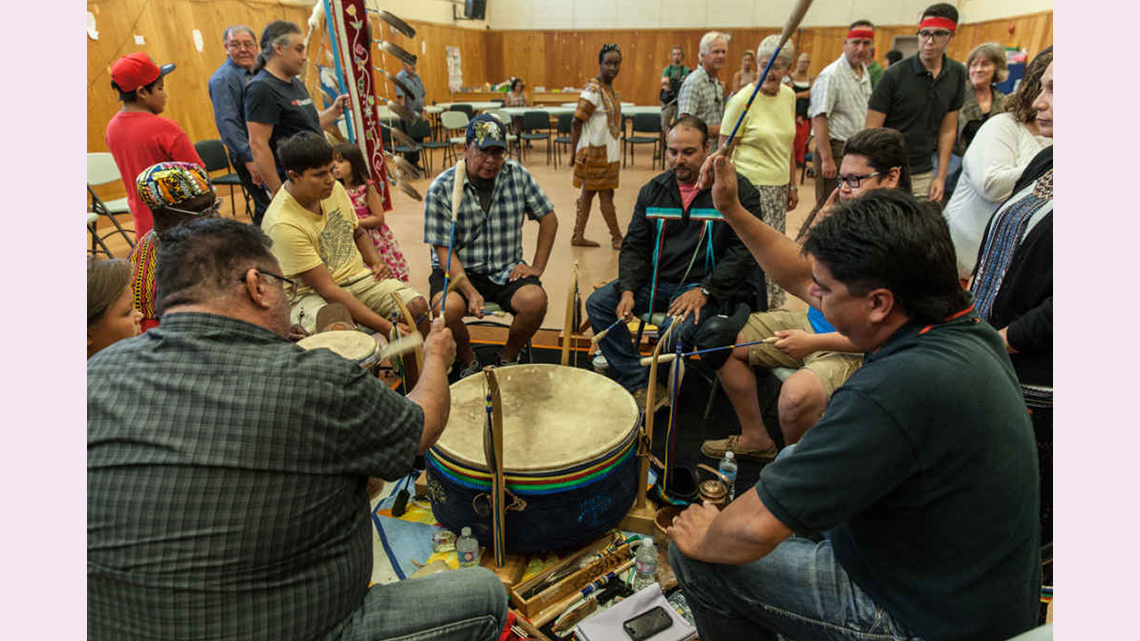 A group of men around a drum with people looking on.