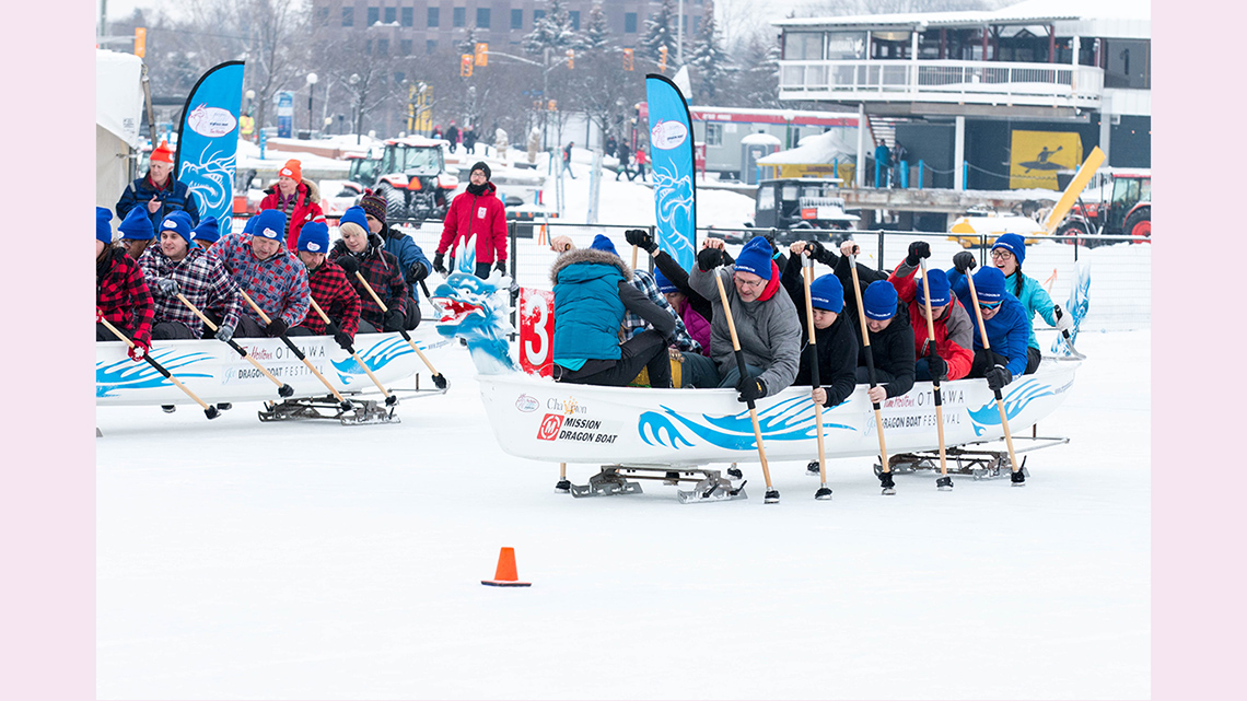 Teams of people racing dragon boats along the ice of the frozen Rideau Canal.