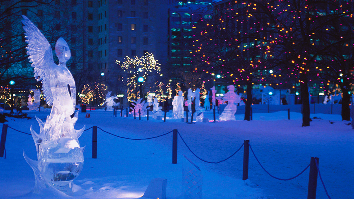 A park at night with illuminated ice sculptures.