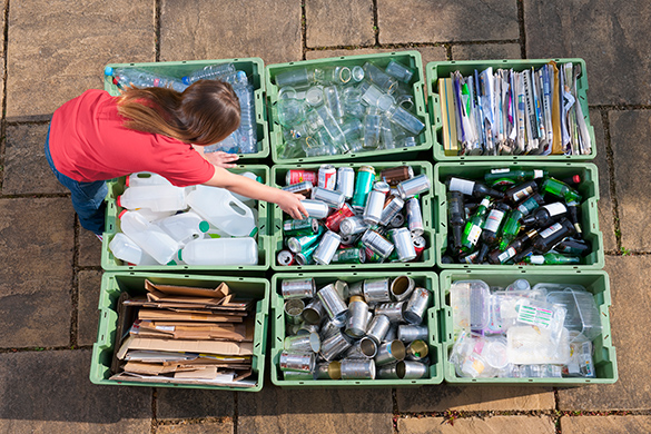 A child leans over nine full recycling bins.