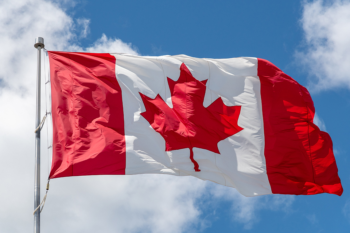 A flag of Canada in the blue sky.