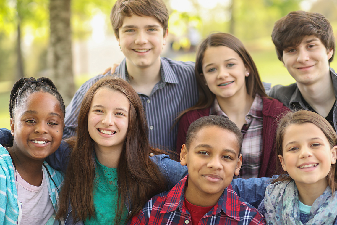 A group of students with their arms on one another's shoulders smiling for a photo.
