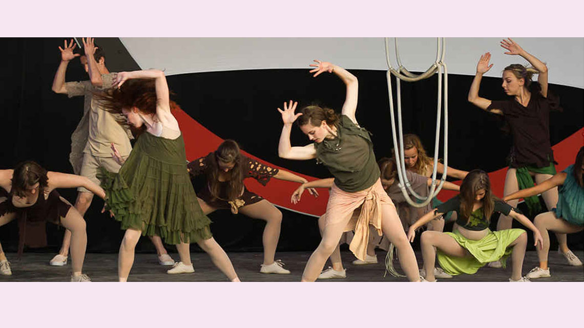 A group of teen performers perform a dramatic interpretive dance onstage.