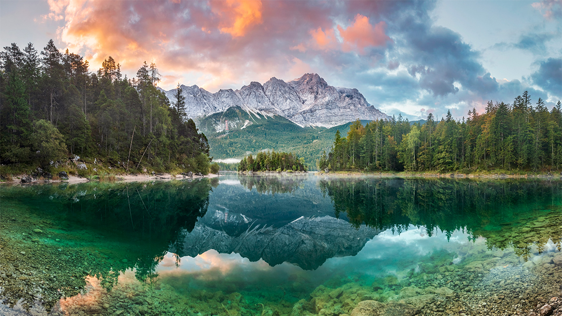 A continental climate with green forests and snow on the mountains.
