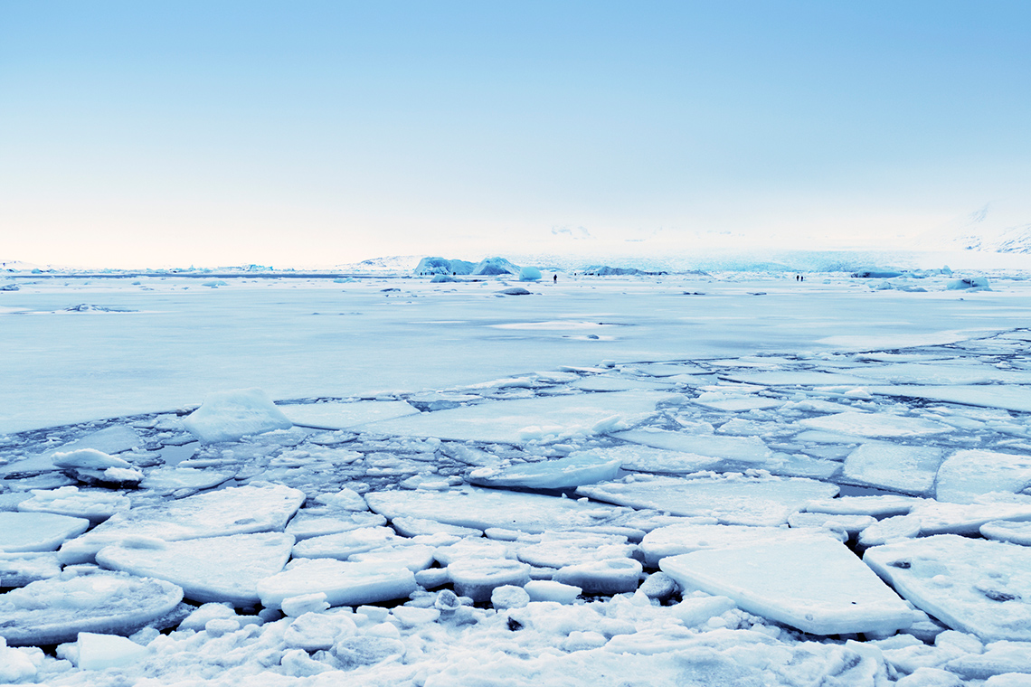 Flat expanse of ice-covered land. The ice in front is breaking, and is flat in the distance.