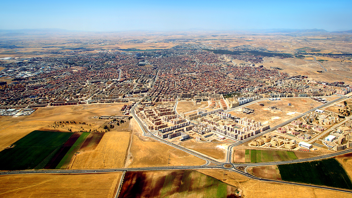 An aerial view of Sétif, Algeria with large fields. roads, and a town in the background.