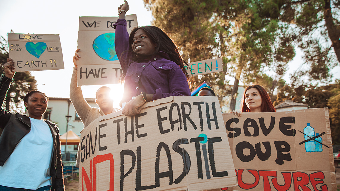 A group of demonstrators hold up signs against plastic pollution.