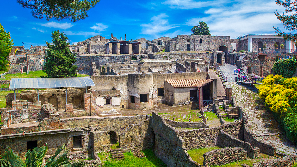 A panoramic view of the ancient city of Pompeii with deserted stone houses and streets.