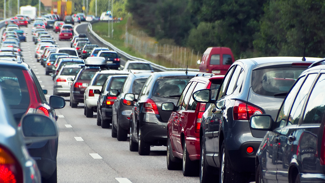 This image depicts a three-lane highway. Each lane is packed with cars bumper to bumper.