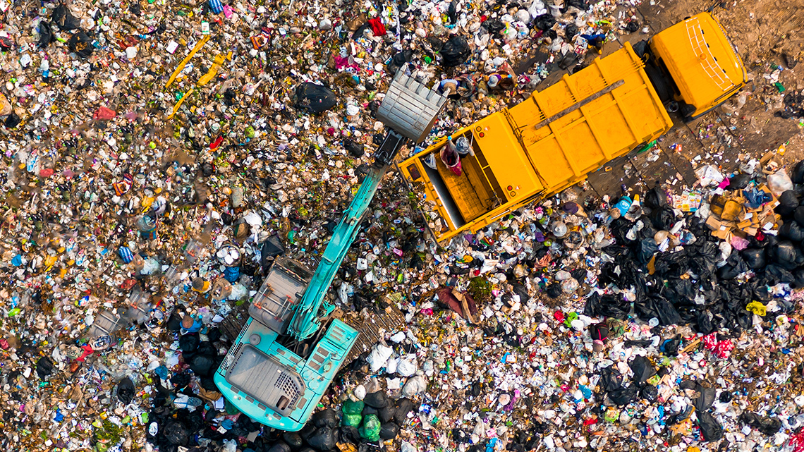 This is an aerial photo of a dump full of garbage with a truck dumping more garbage.