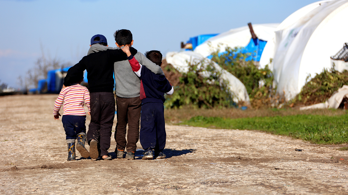 Waiting for a New Settlement at a Refugee Camp in Syria Four children hug as they walk along their refugee camp