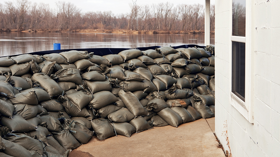 Flood Preparation with Sandbags A house surrounded by a wall of sandbags, with flood waters being held back behind the
sandbags