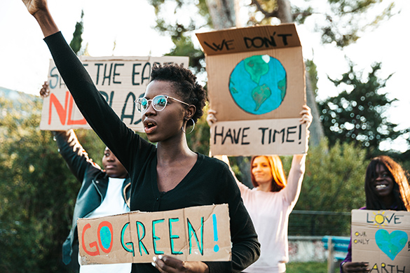 Four people holding up protest signs to encourage people to go green and reduce the use of plastic.