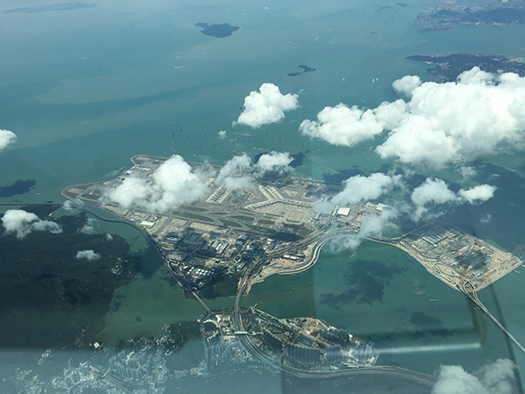 Aerial photograph of Hong Kong airport viewed from above with some scattered clouds.
