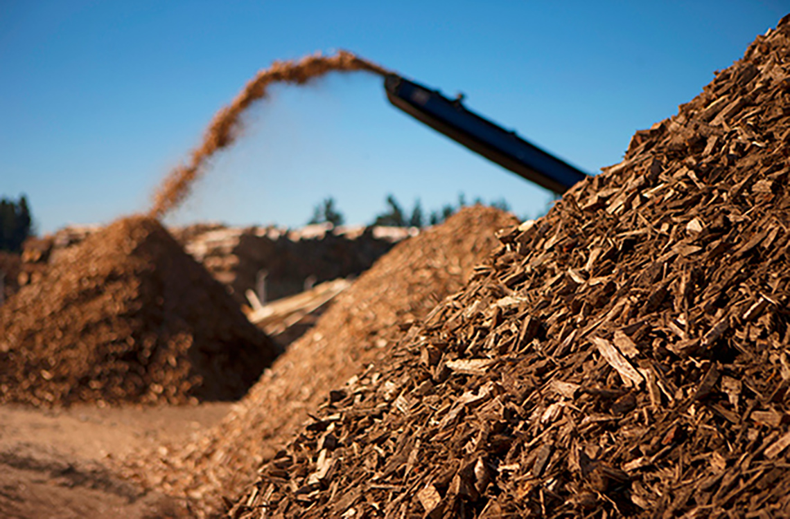 A machine moving wood chips into piles.