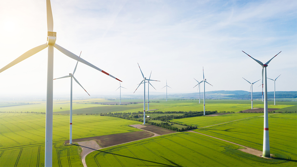 Wind Turbines Creating Wind Power A green field with tall wind turbines turning.