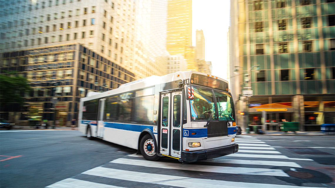 Public Transportation in New York City A bus crossing a crosswalk in a downtown city.