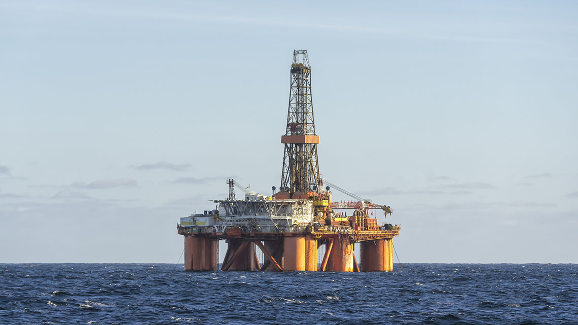 An oil platform in the ocean. Equipment and rooms are on top of the platform, supported by 4 legs.