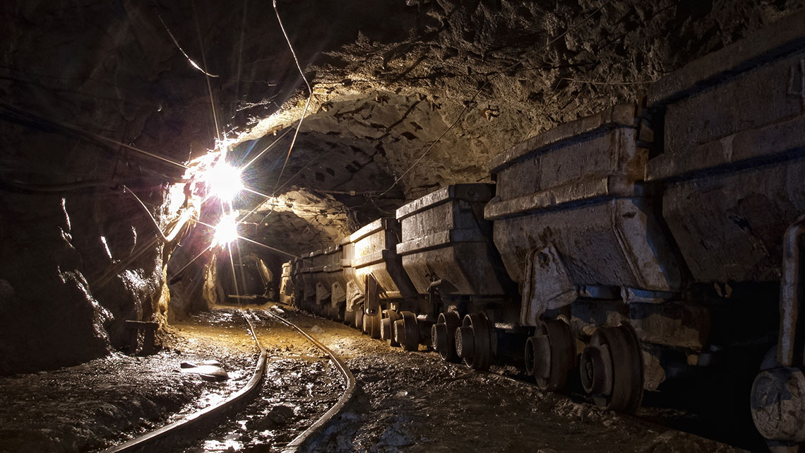 Mining carts on a track deep inside a roughly made mine.