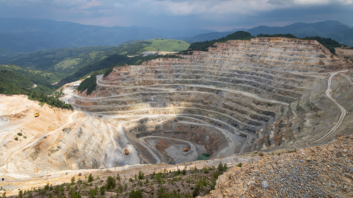 Shows a large open pit mine in Mongolia. The land is pristine aside from the mine.