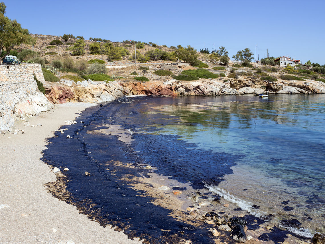 A beachfront with oil washing up on the shore.