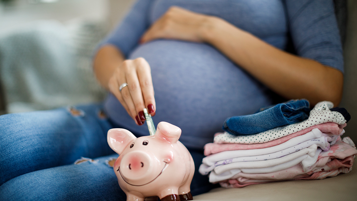 Image of a pregnant woman putting some money into a piggy bank.