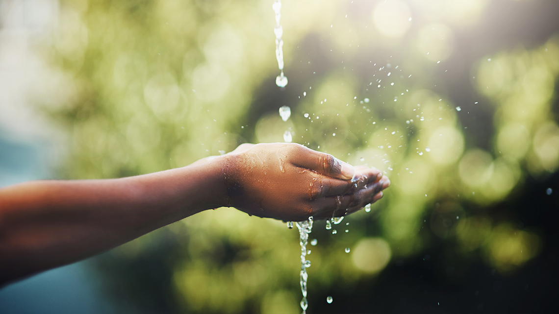 A stream of water being poured into a person’s hands.