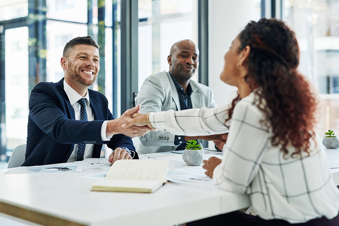An interviewer shakes an interviewee's hand at a job interview.