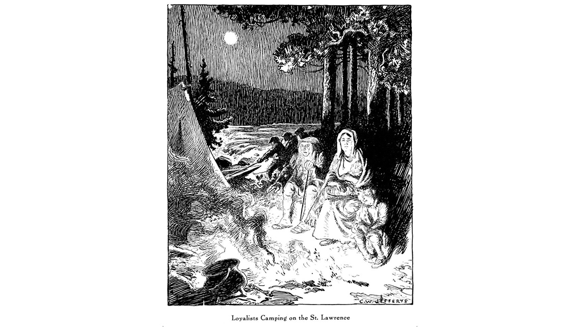 Black & white image of a few people sitting in front of a fire outside of their tent.