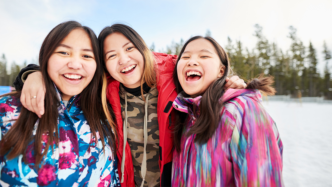 Three people dressed for winter and enjoying being outside.