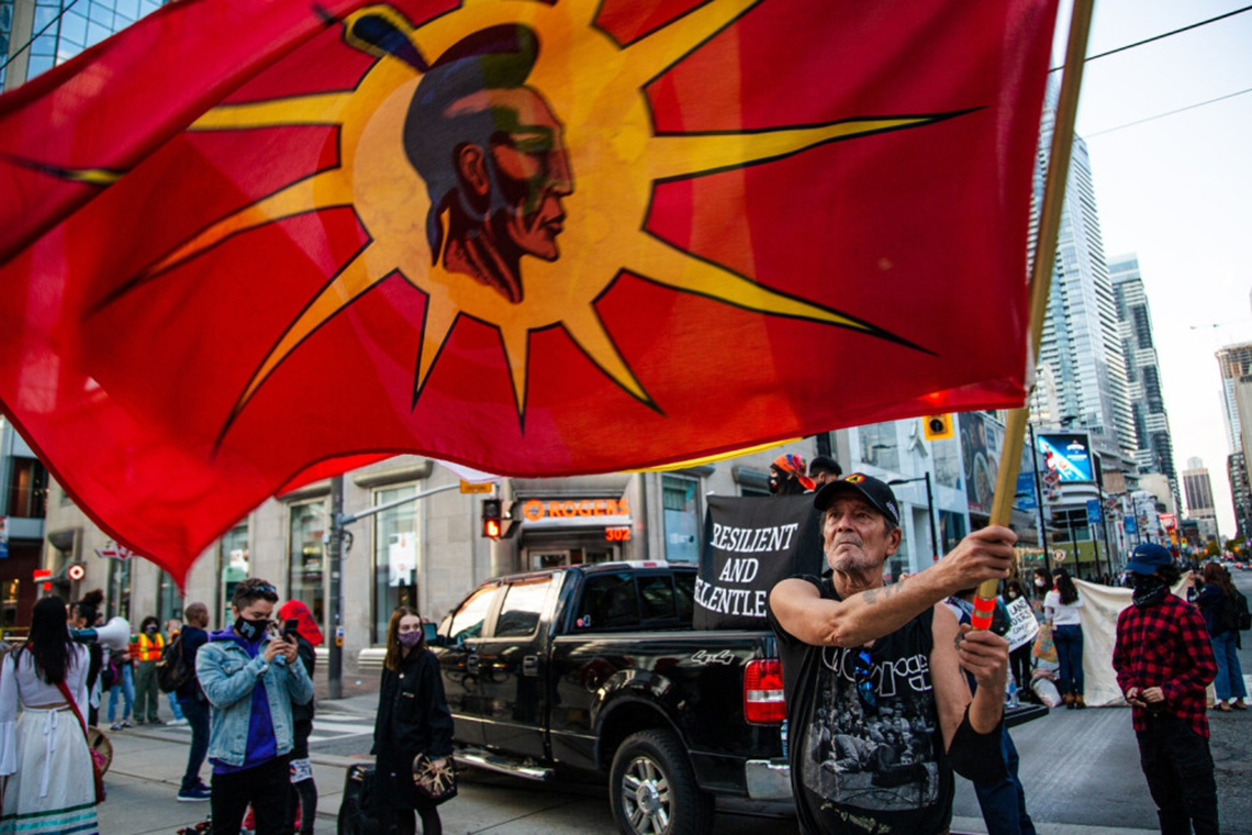 An image of an Indigenous flag being held by a person at the protest.