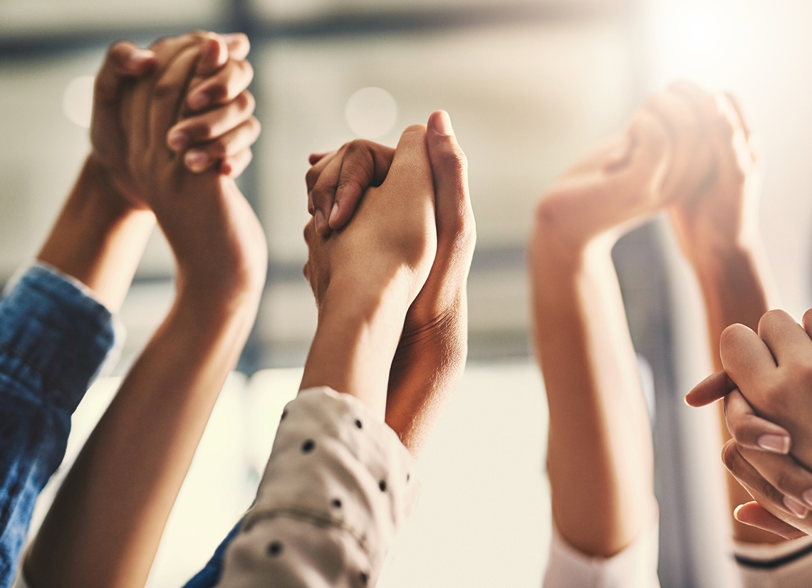 Several people raise their clasped hands together in the air.