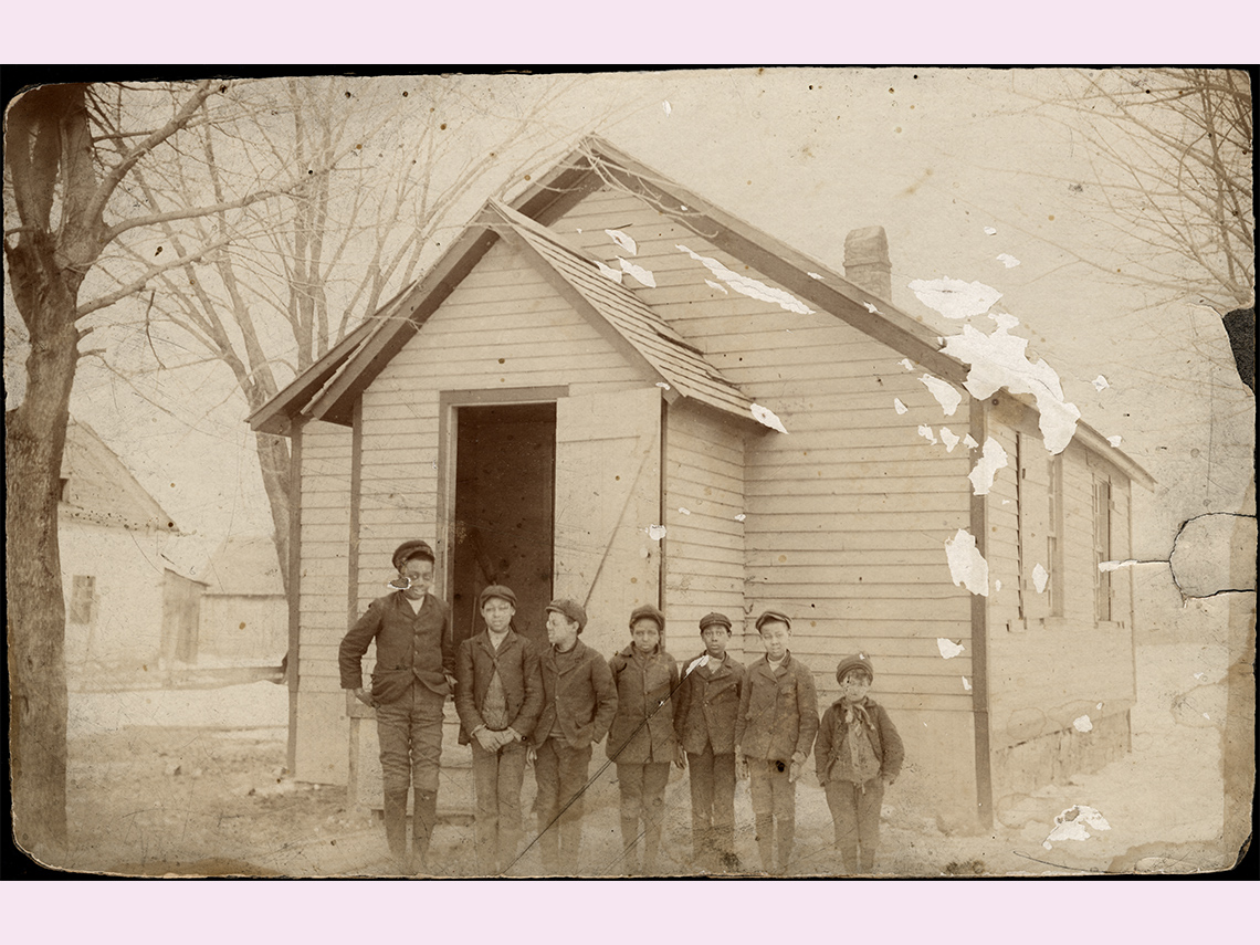 A group of Black children stand in front of a school in rural Ontario, around the year 1900.