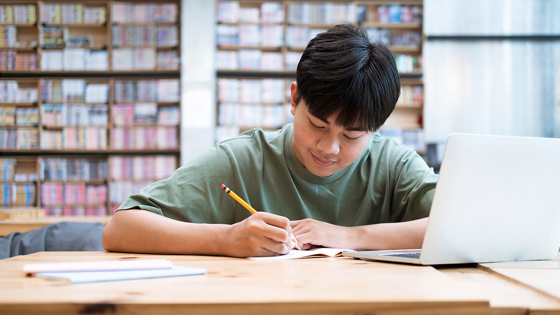 A student on a desk writes notes.