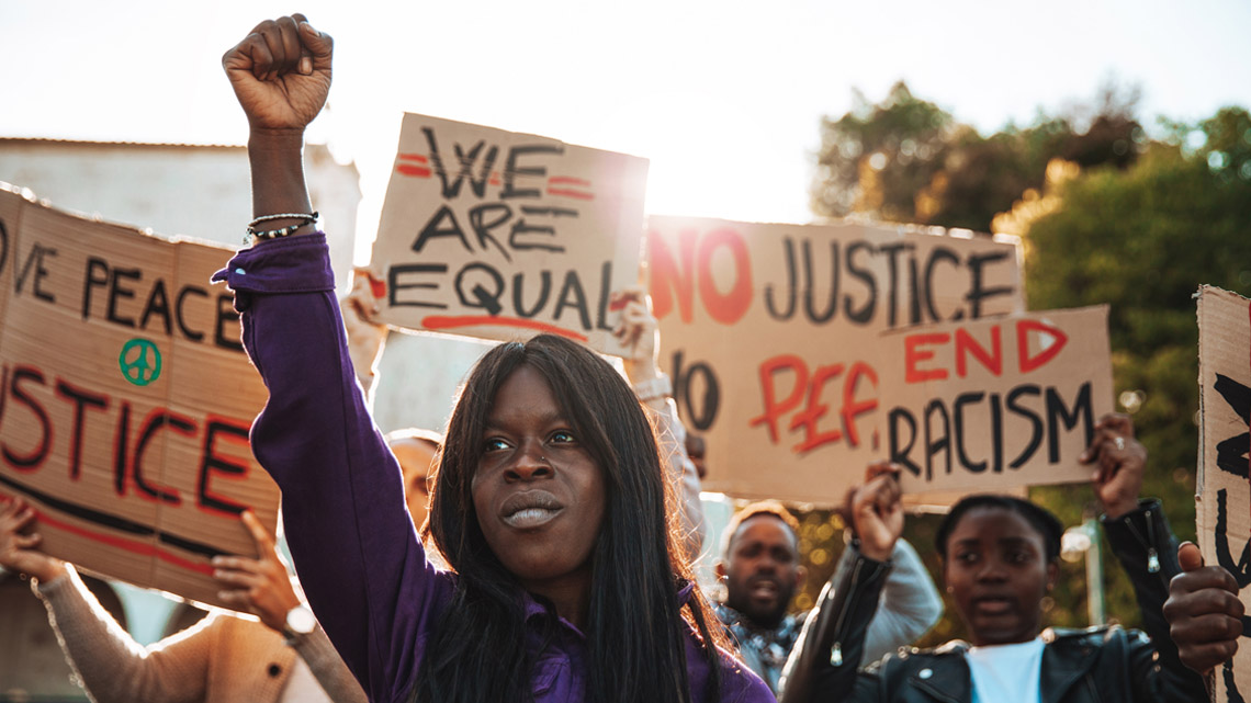 People holding protest signs for anti-racism.