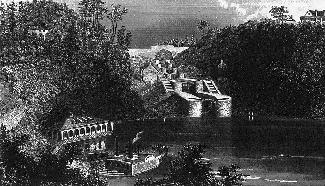 A canal with high lands with trees on both sides. In the center is a water way.