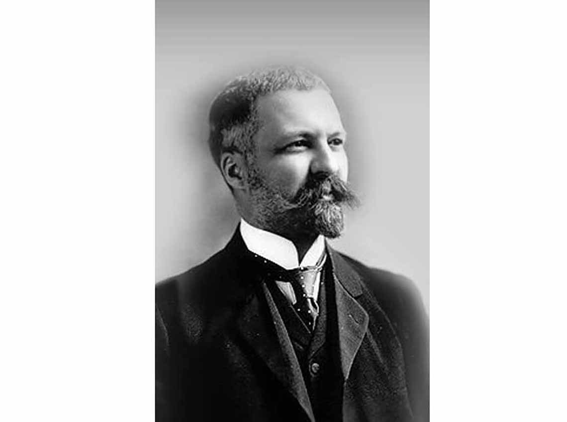 This is a portrait of Heni Bourassa. He has short hair and a moustache. He is wearing a suit.