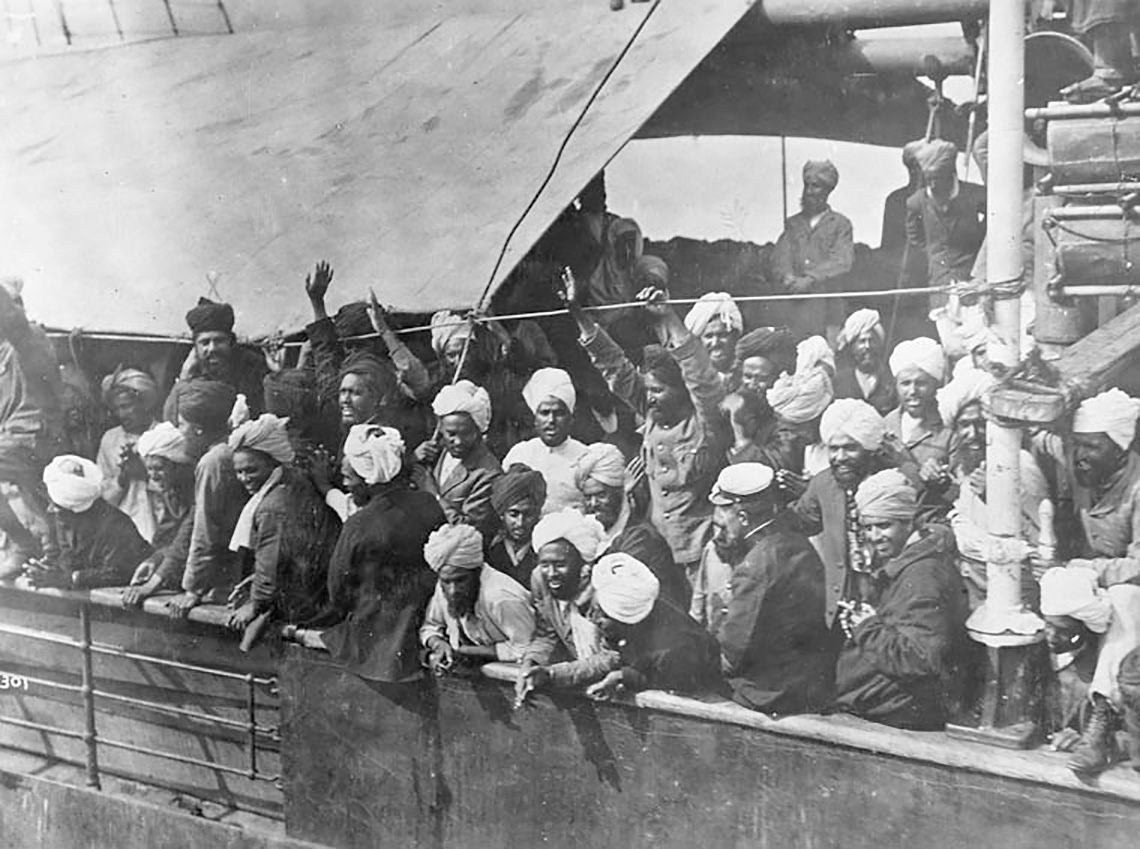 A group of Sikh passengers on the deck of a ship. Some are waving 