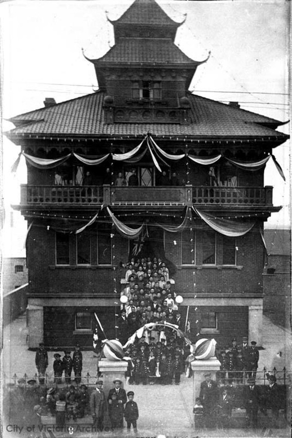 Many people gathered to celebrate the grand opening of the new Chinese school, an ornate multi-story building. 