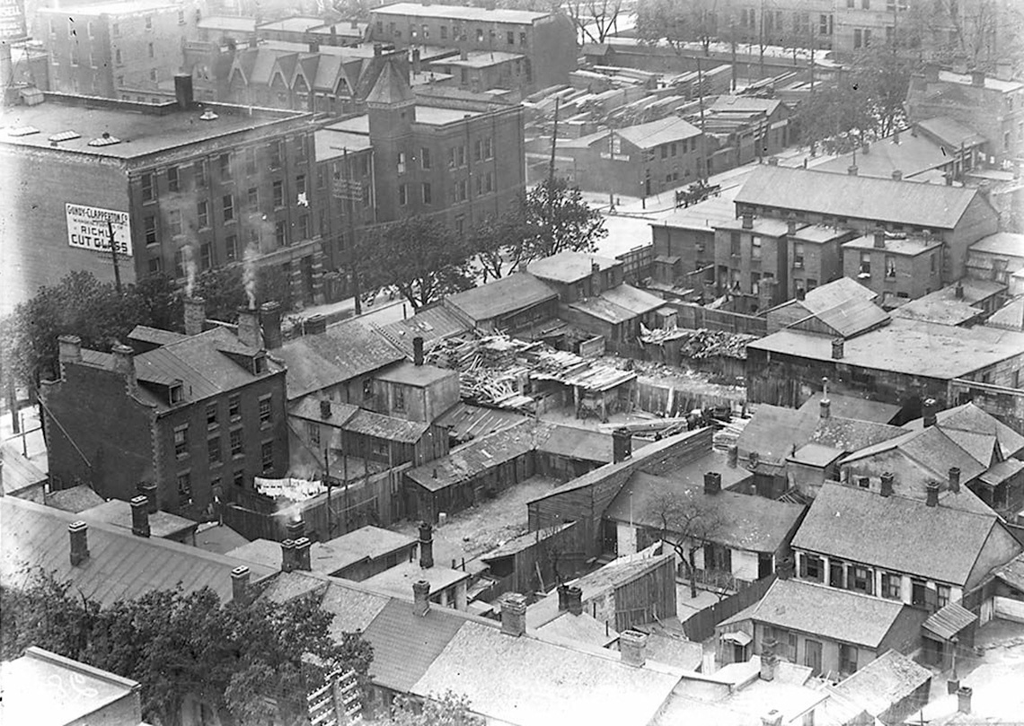 An aerial view of an urban neighborhood. Houses and factories are very close together.