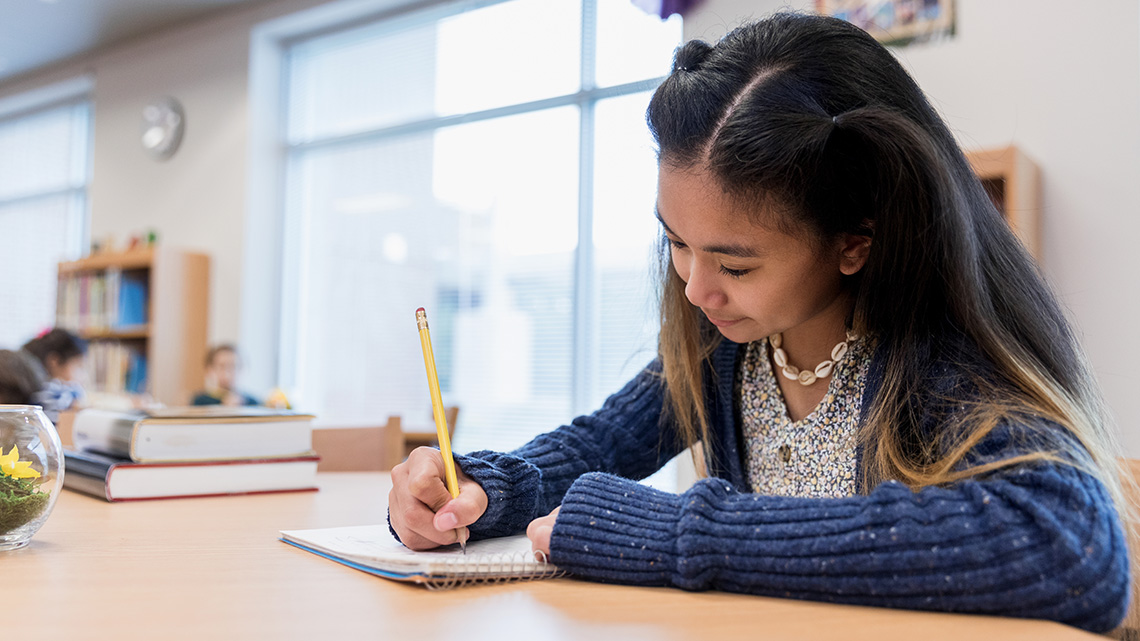 A student on a desk writing notes