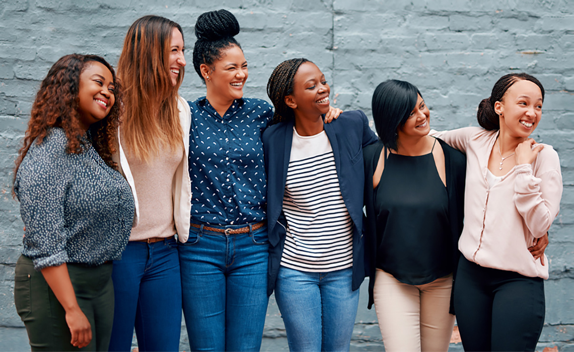 Women of different nationalities standing together facing the same direction.