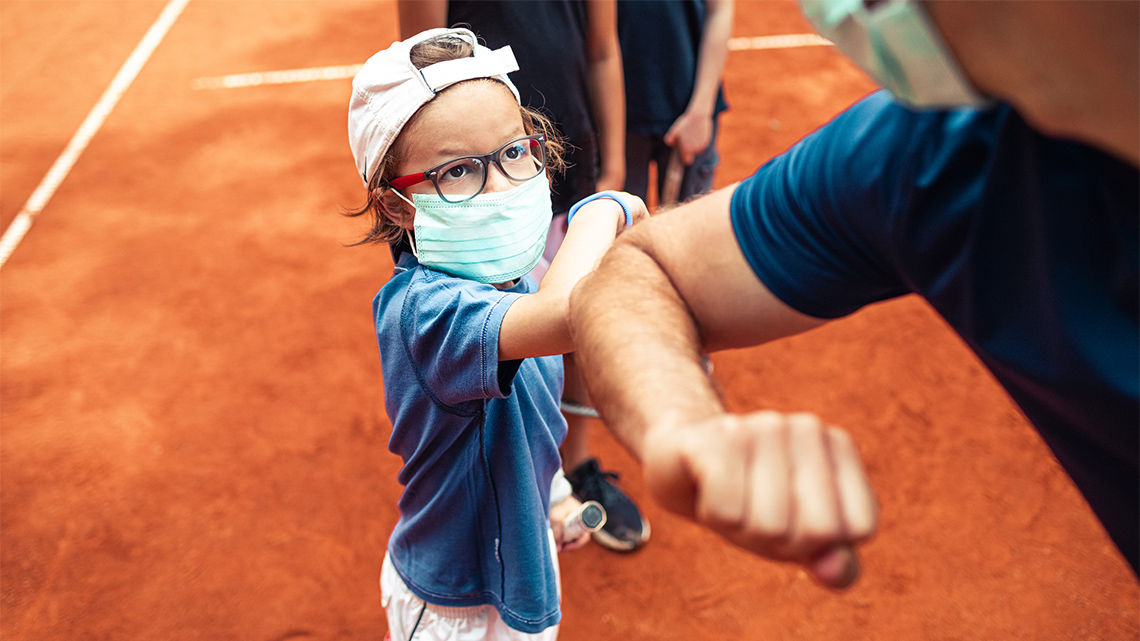 A child and an adult bump elbows after playing a sport.