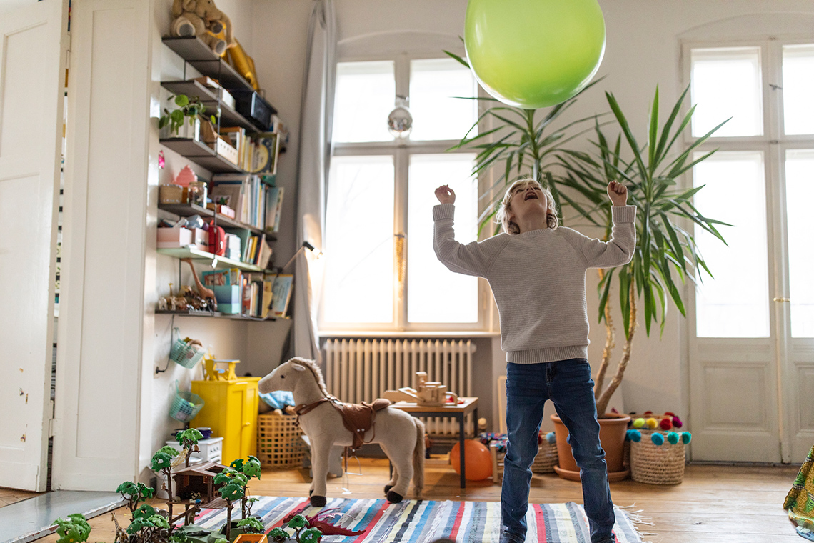 A child is playing with a balloon and keeping it up in the air.