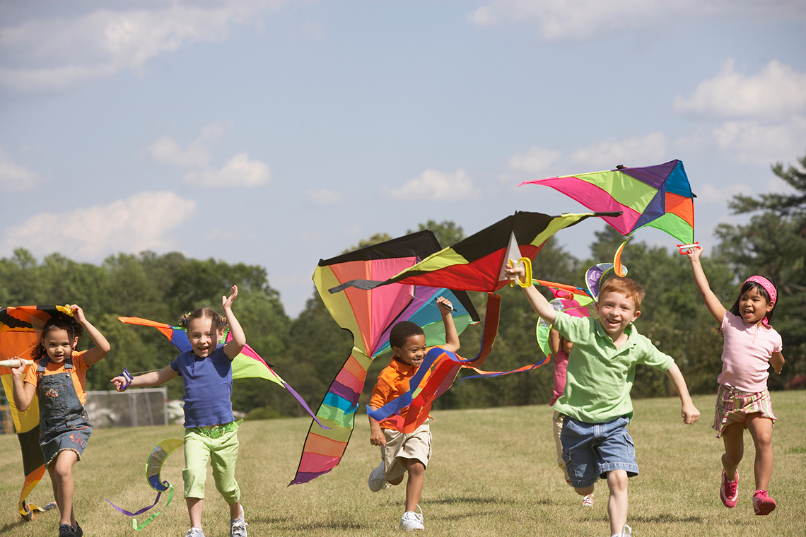 Children with big, happy smiles are all flying kites.
